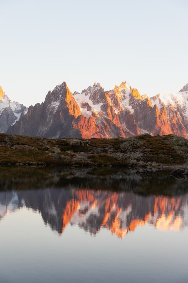 Alpenglow peaks mirrored in the still lake at Lacs des Cheserys