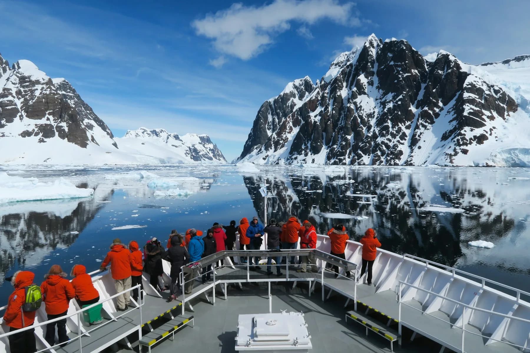 An expedition ship sailing into the Lemaire Channel between snowy Antarctic peaks