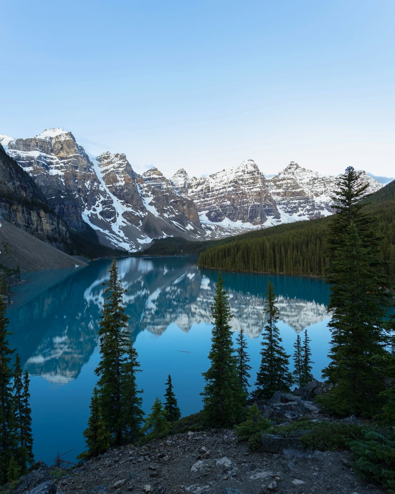 Moraine Lake mirroring the Valley of the Ten Peaks, seen from the Rockpile between tall conifers