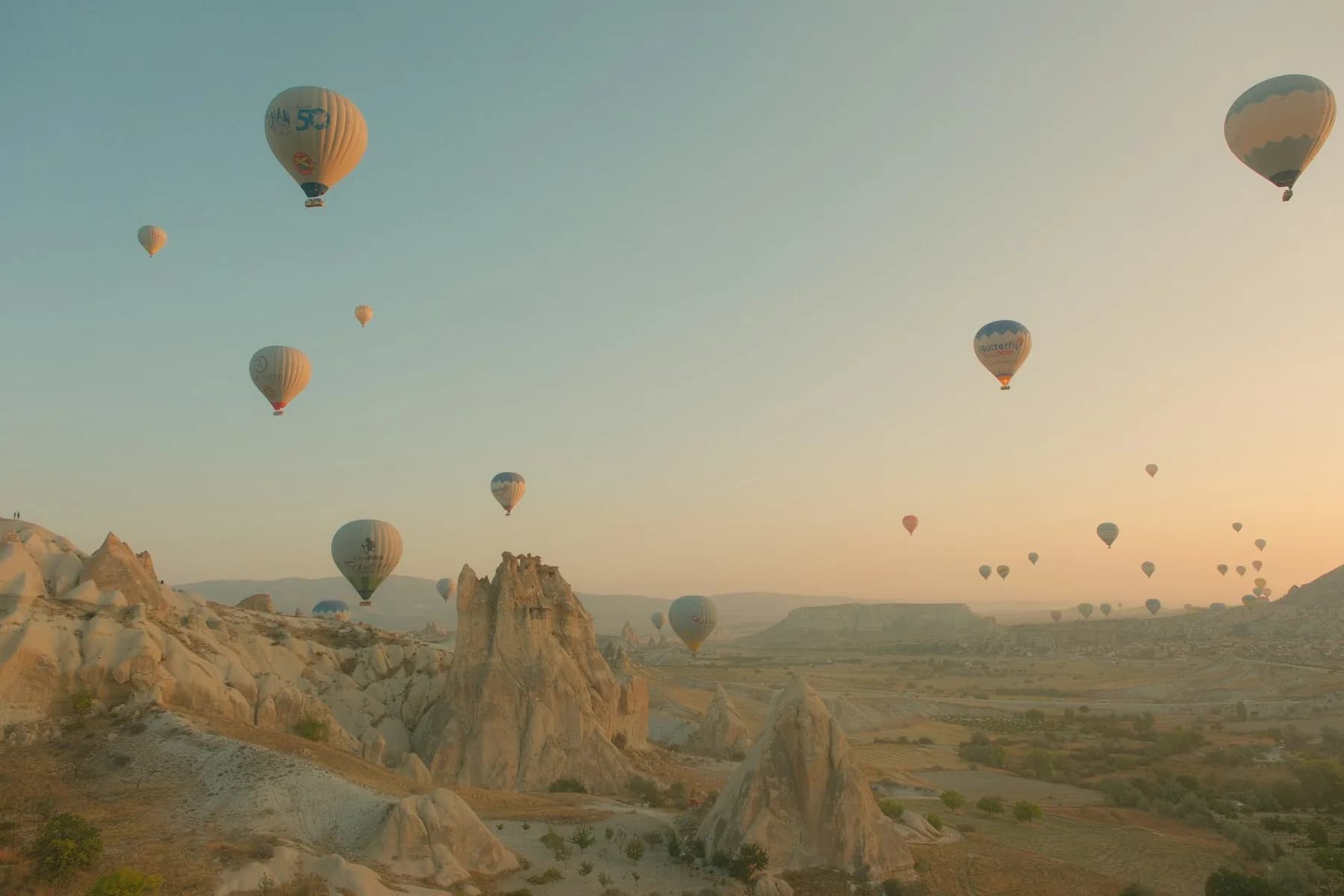Hot air balloons drifting over the fairy chimneys of Goreme at dawn