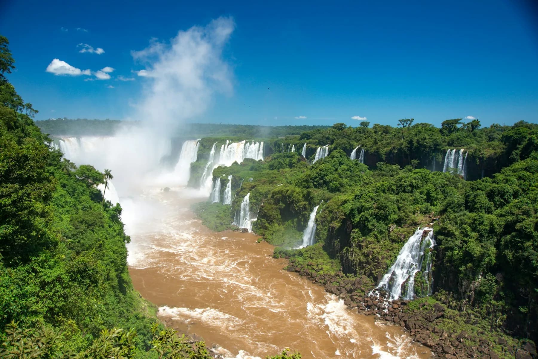 Iguazu Falls pouring into the gorge with mist rising over the rainforest
