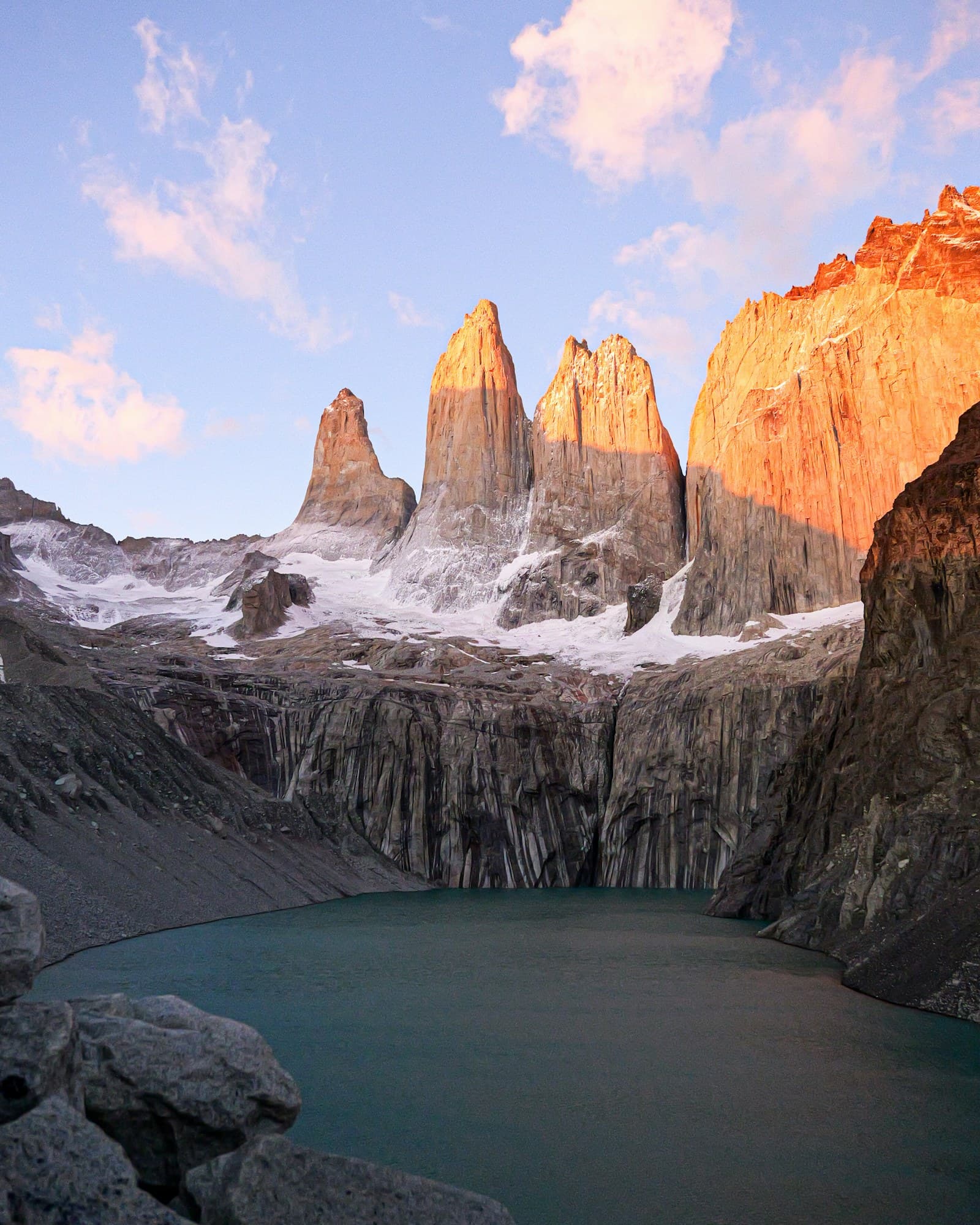 The three granite towers of Torres del Paine glowing at sunrise above the glacial lagoon